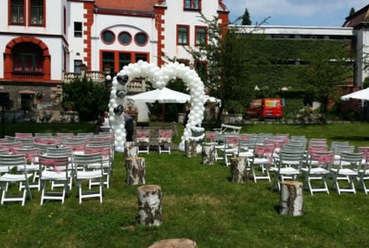 Ballon Moments - Dekoration - Weißer Ballonbogen über Stuhlreihen im Garten