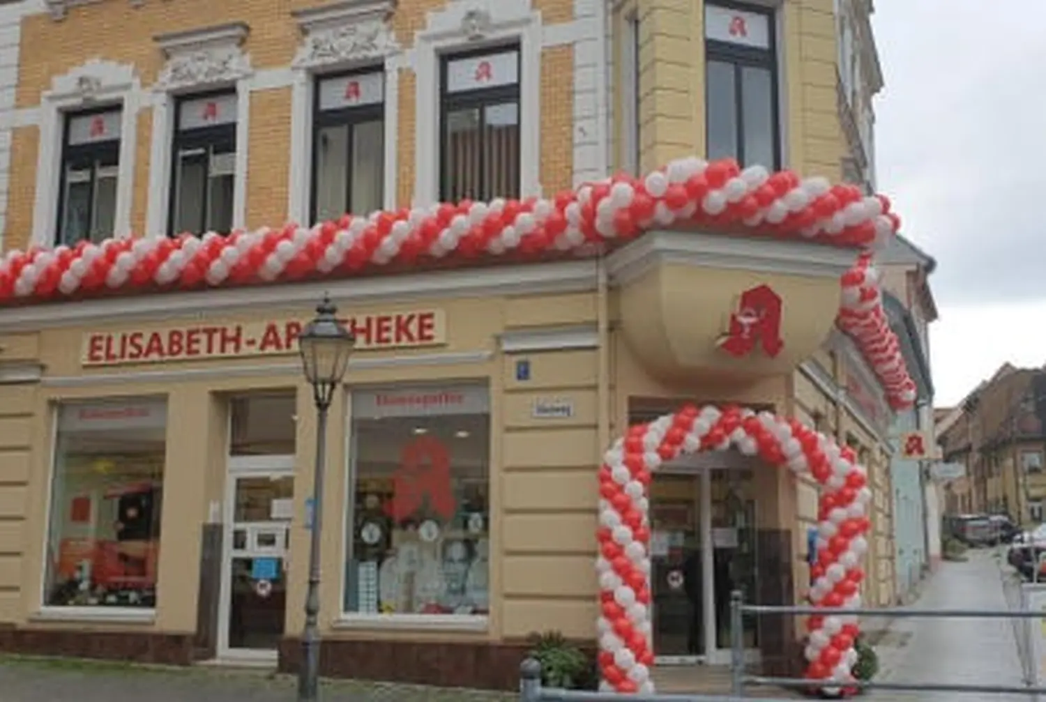 Ballon Moments - Dekoration -Rot-weißer Ballonbogen vor Apotheke