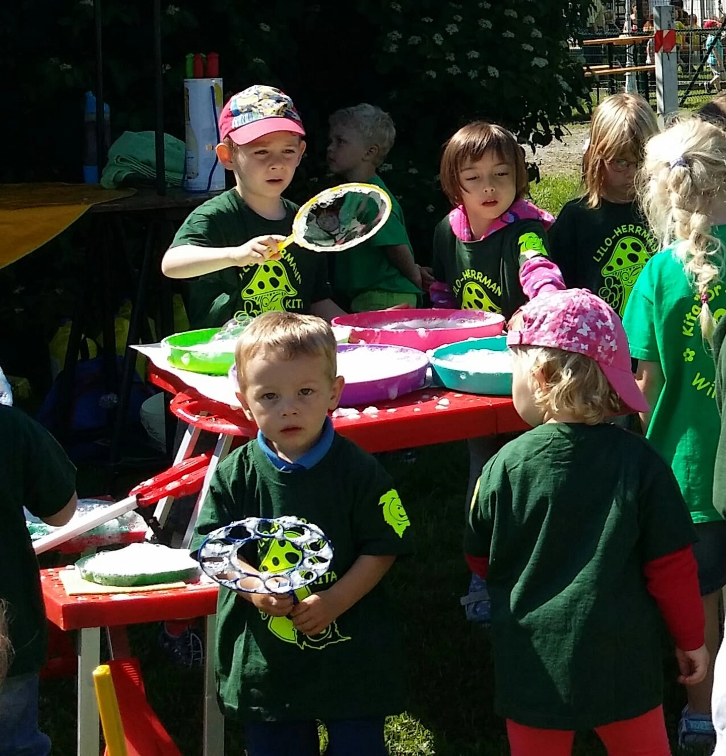 Moments Veranstaltungsagentur - Kinder machen Seifenblasen an einem Tisch im Freien