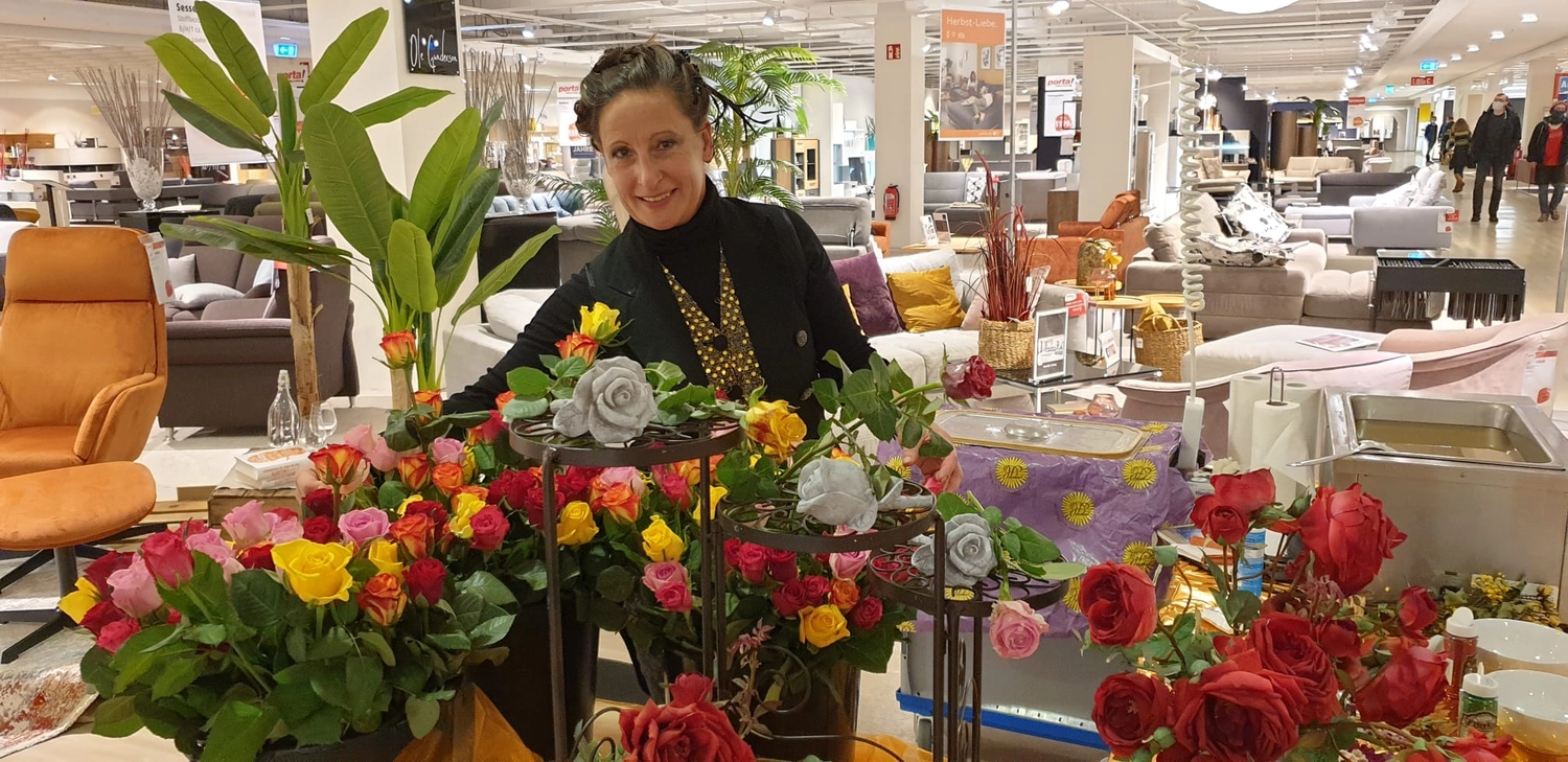 Moments Veranstaltungsagentur -  Frau mit Wachsrosen-Dekoration im Geschäft