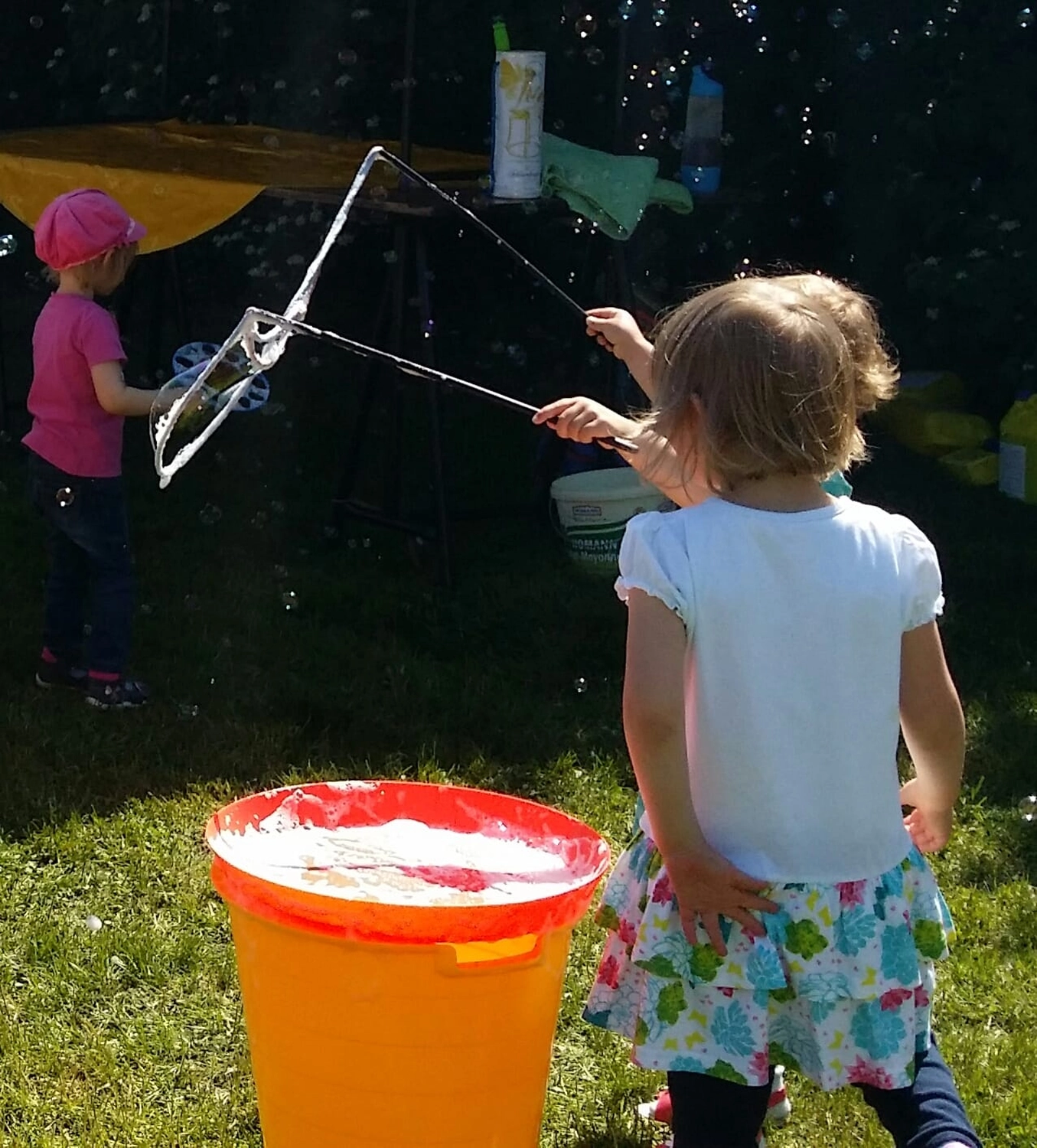 Moments Veranstaltungsagentur -  Kind macht Riesenseifenblasen im Garten