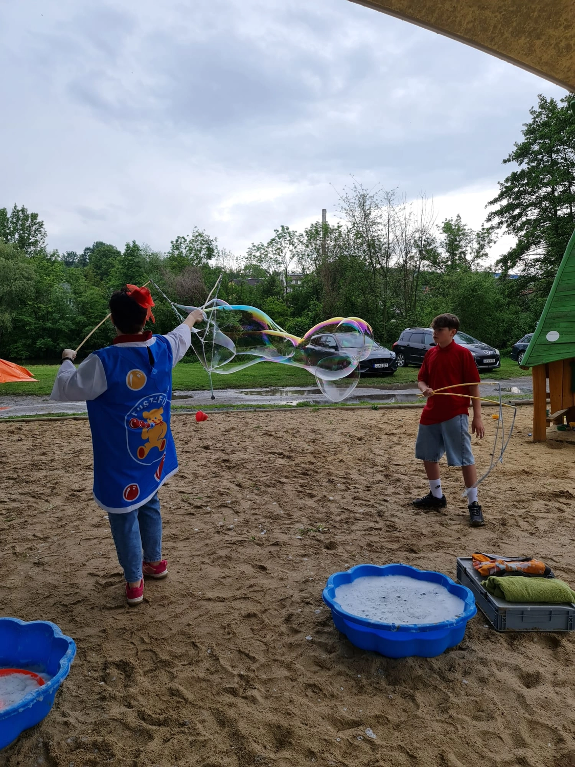 Moments Veranstaltungsagentur - Kinder ziehen große Seifenblase über Sandplatz