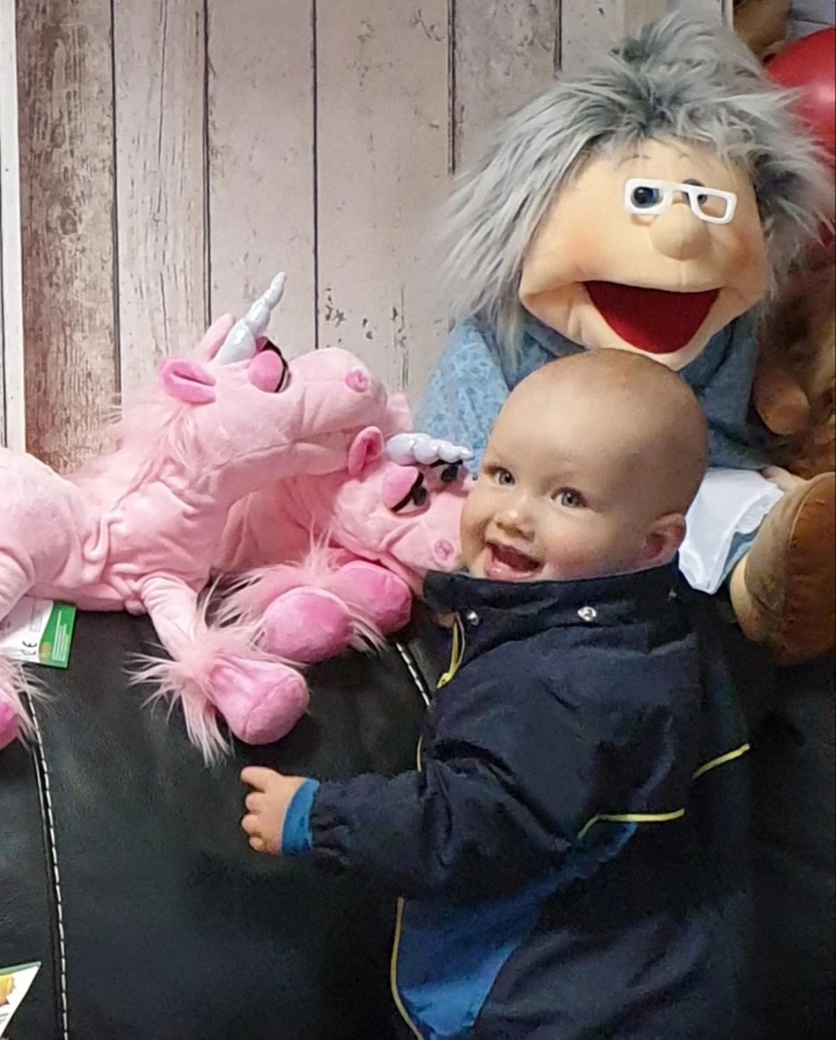 Moments Veranstaltungsagentur -  Baby lacht mit Handpuppe und Einhorn-Kuscheltier